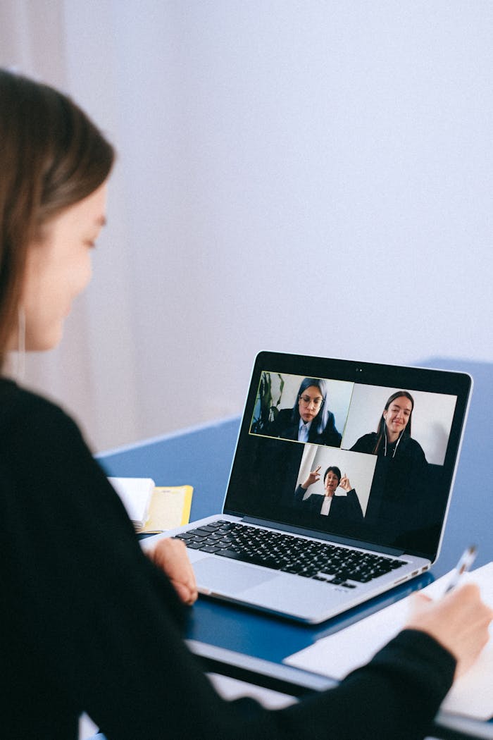 who-we-are A woman participates in a virtual meeting with colleagues via video call on a laptop.